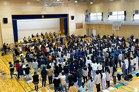 小学校体育館で、オーケストラ演奏を熱心に聴く児童